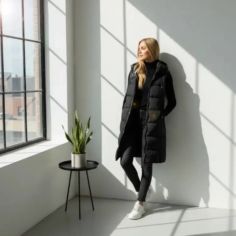 Parka femme : 10 modèles polyvalents et stylés 2025, femme en parka noire élégante près d'une fenêtre. Image